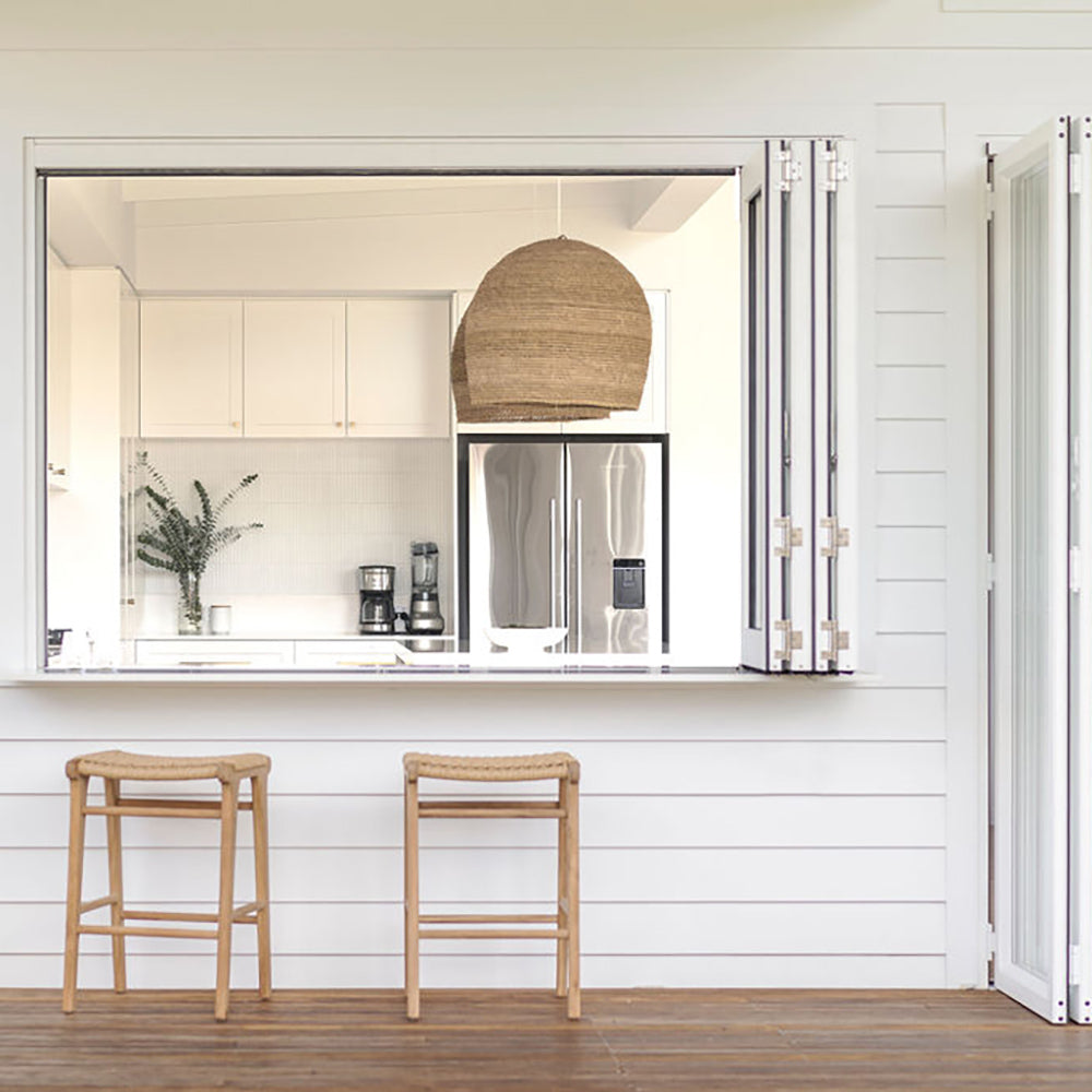 Pair of Zen Backless Bar Stools – Sand – Open Weave at a coastal-style servery window with white cladding.