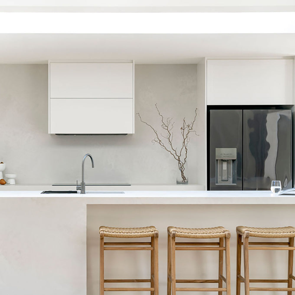 Straight-on view of three Zen Backless Bar Stools – Sand – Open Weave at a minimalist white kitchen counter.