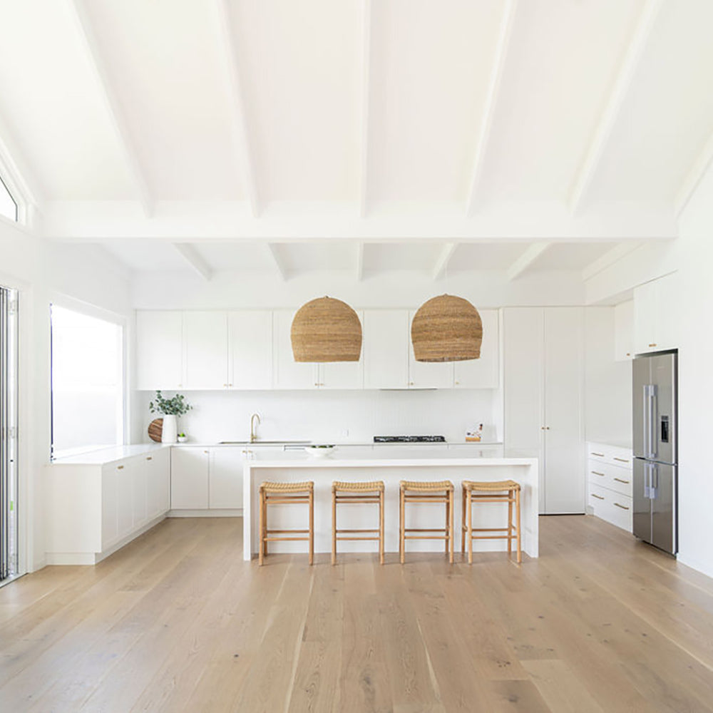 Full interior shot of a coastal kitchen featuring four Zen Backless Bar Stools – Sand – Open Weave and vaulted ceiling.
