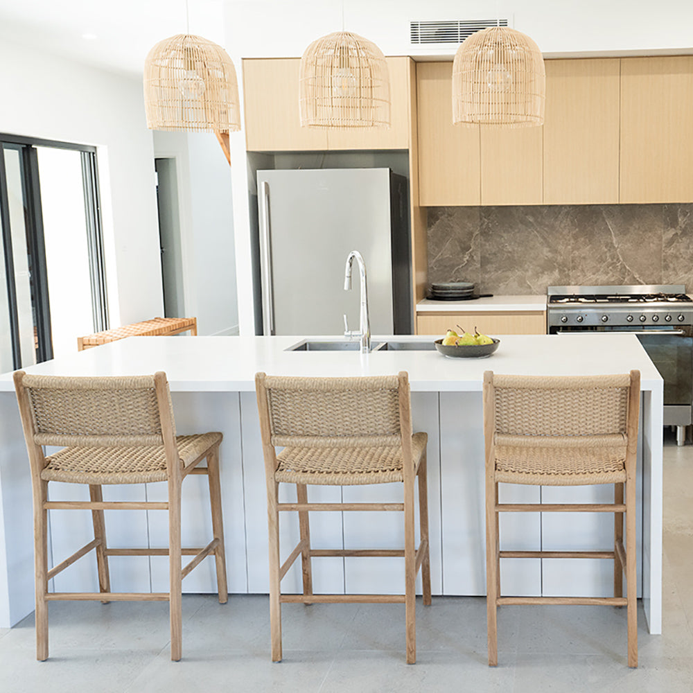 Rear kitchen view of Zen Counter Stools – Sand – Close Weave neatly arranged at a white island beneath rattan pendant lights.