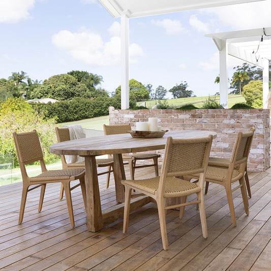 Outdoor lifestyle setting featuring six Zen Dining Chairs – Sand – Close Weave arranged around a timber dining table on a covered deck.