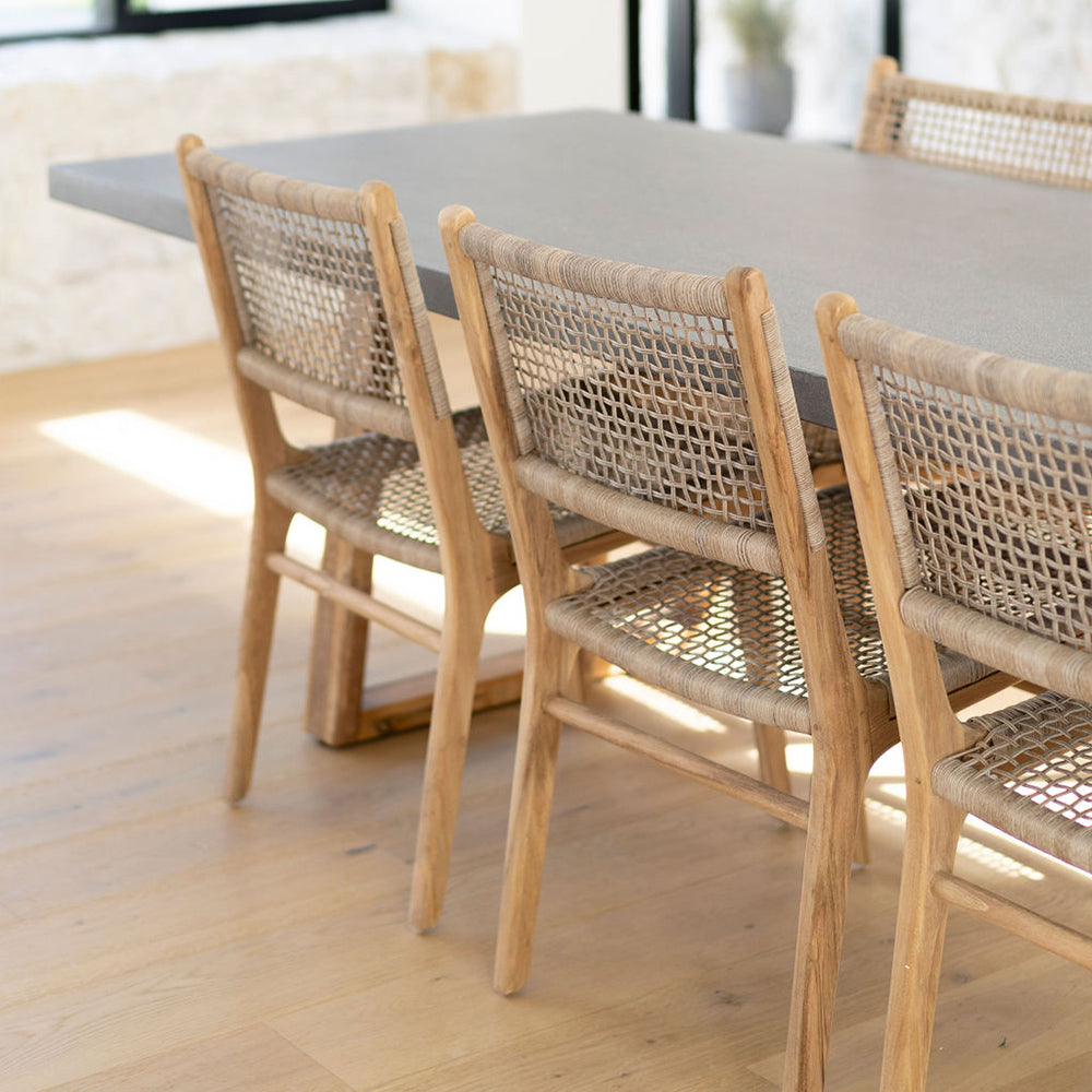 Close-up of Zen Dining Chair – Washed Grey – Open Weave styled around a concrete dining table on timber flooring.