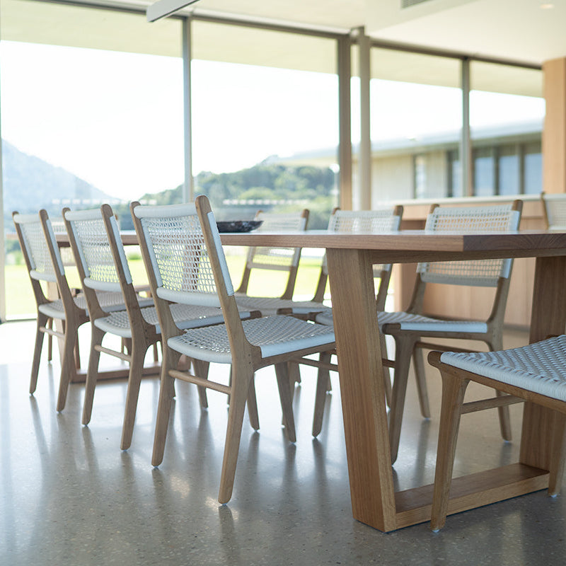 Indoor dining setting featuring Zen Dining Chairs – White – Open Weave paired with a modern timber table and mountain view backdrop.