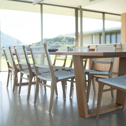 Indoor dining setting featuring Zen Dining Chairs – White – Open Weave paired with a modern timber table and mountain view backdrop.