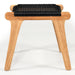 Side profile of the Zen Lazy Chair Ottoman in Black, showcasing sculpted teak wood legs and a slightly curved seat wrapped in handwoven black rope for minimalist yet bold seating design.