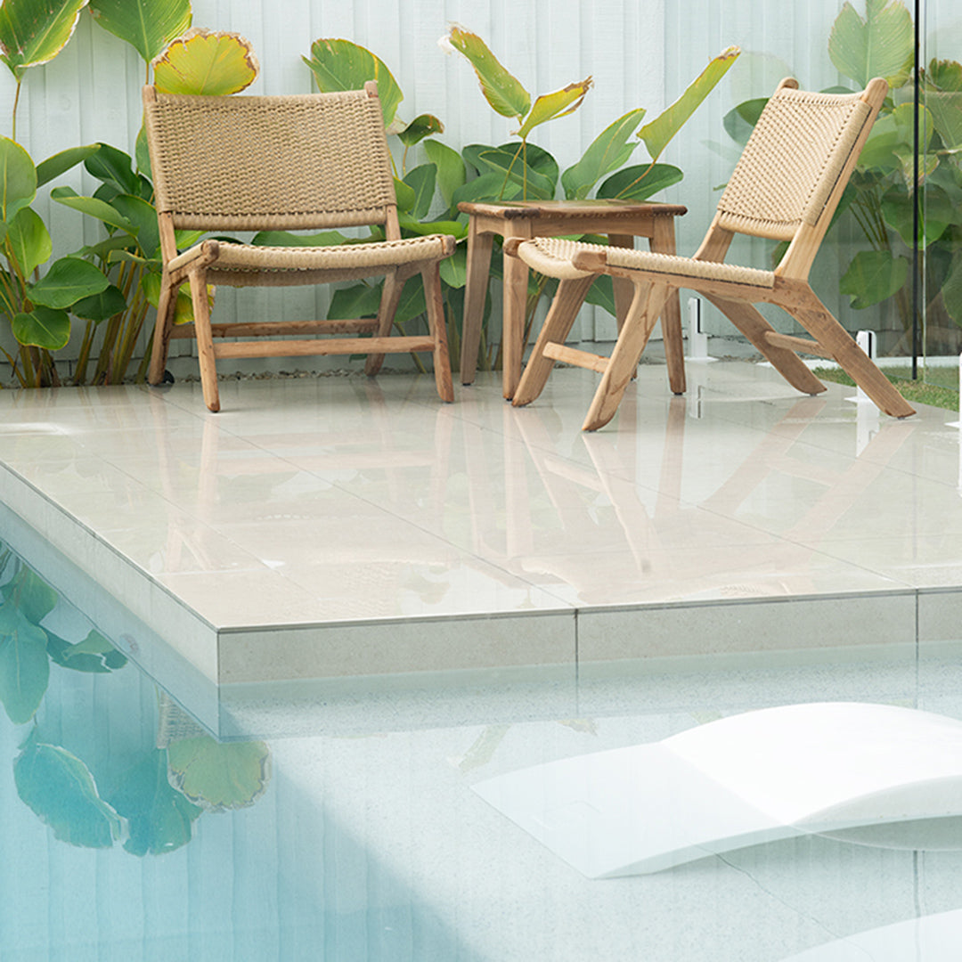 Zen Lazy Chairs in Sand styled poolside with teak side table and tropical foliage, creating a relaxed outdoor setting.