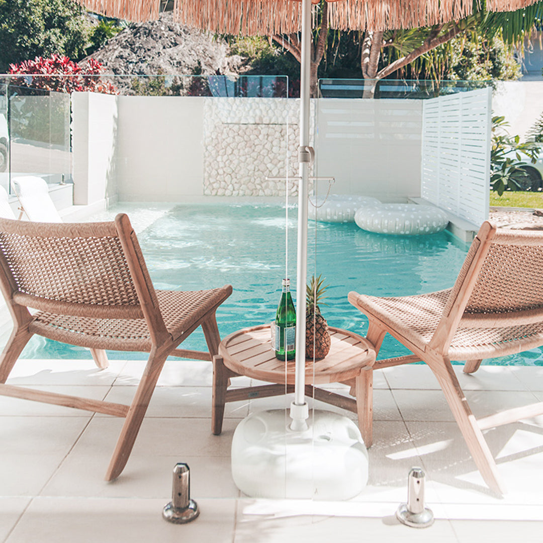 Back view of two Zen Lazy Chairs – Sand – flanking a teak side table, overlooking a private plunge pool and floating loungers.
