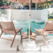 Back view of two Zen Lazy Chairs – Sand – flanking a teak side table, overlooking a private plunge pool and floating loungers.