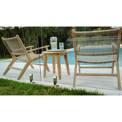 Poolside view of two Zen Lazy Chairs - Sand - Open Weave placed beside a round teak side table on a tiled patio. The chairs showcase sand-toned synthetic rope in an open-weave pattern on natural teak wood frames, with reflections visible in the glass fence.