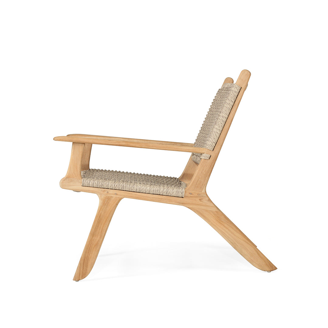 Side profile of the Zen Lazy Chair in Sand, featuring a reclining teak wood frame with sculpted arms and a curved silhouette, paired with a tightly woven seat and back in a close weave pattern.