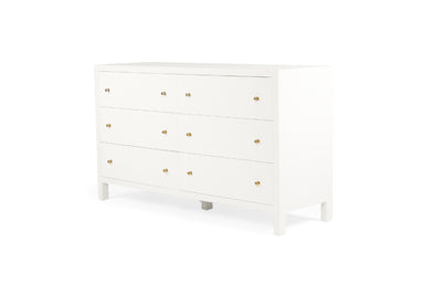 Angled view of the Audrey white six-drawer chest featuring fluted fronts, brass handles and modern timber frame.