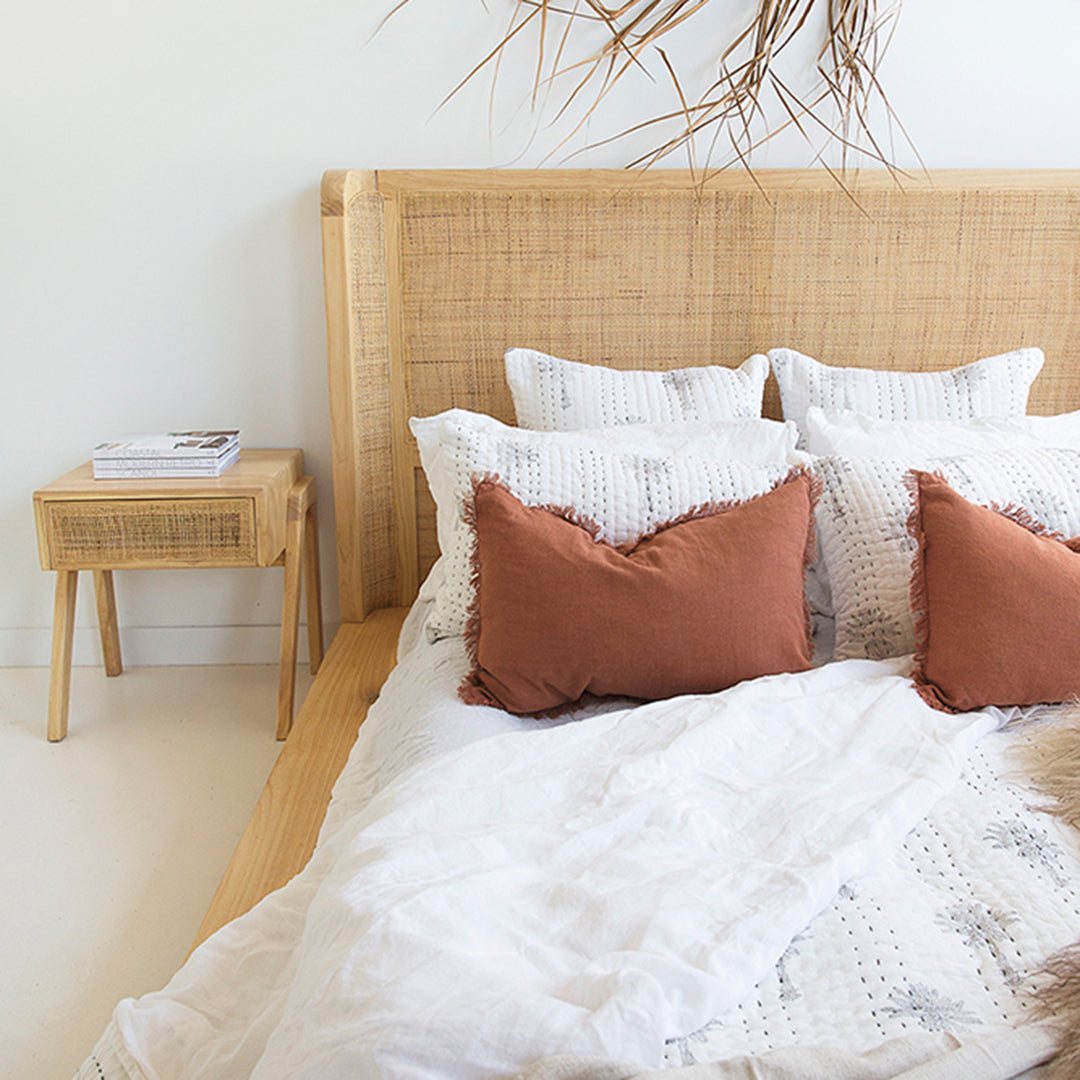 Castaway Bedside Table beside Castaway Bed with rust cushions, white bedding and natural textures