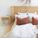 Castaway Bedside Table beside Castaway Bed with rust cushions, white bedding and natural textures
