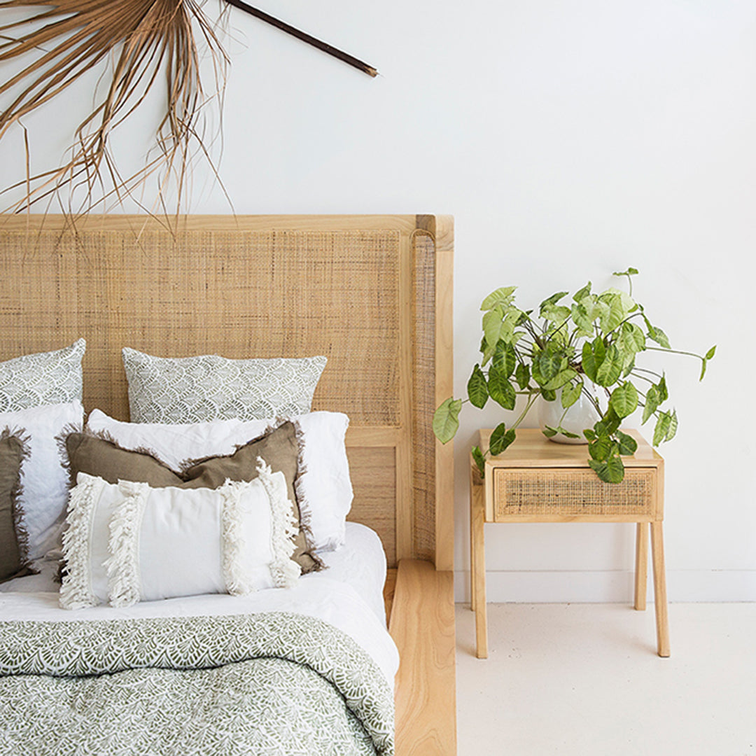 Castaway Bedside Table styled next to an upholstered bedhead with neutral bedding