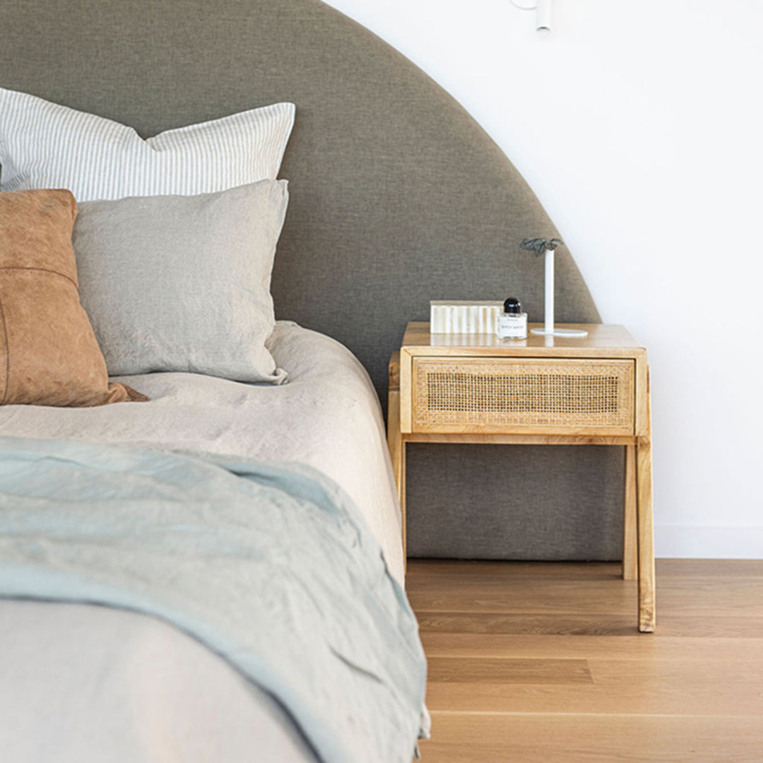 Castaway Bedside Table styled beside an upholstered bed in a soft neutral bedroom