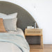 Castaway Bedside Table styled beside an upholstered bed in a soft neutral bedroom
