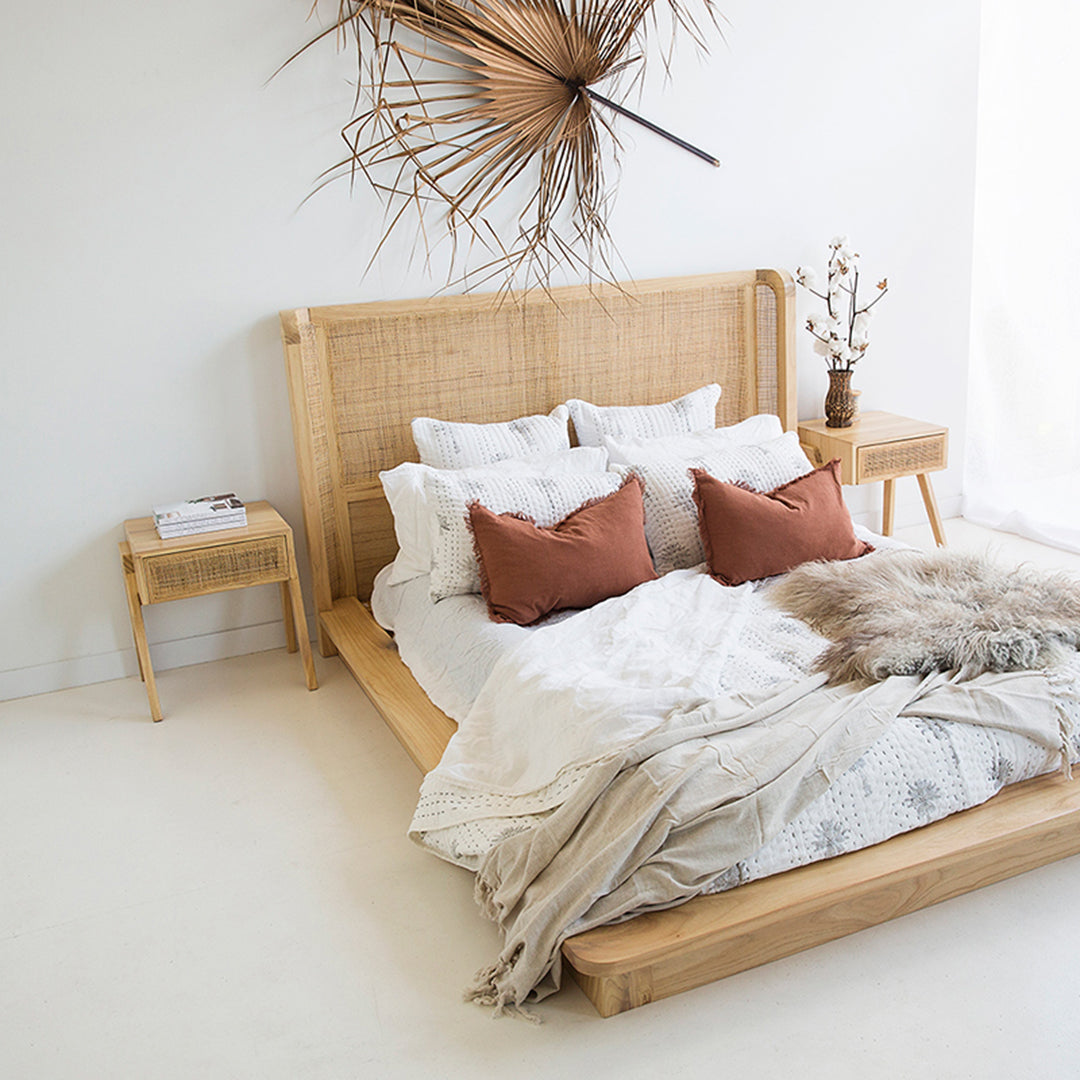 Castaway Bedside Table styled beside a rattan bedhead with cotton stems and white bedding
