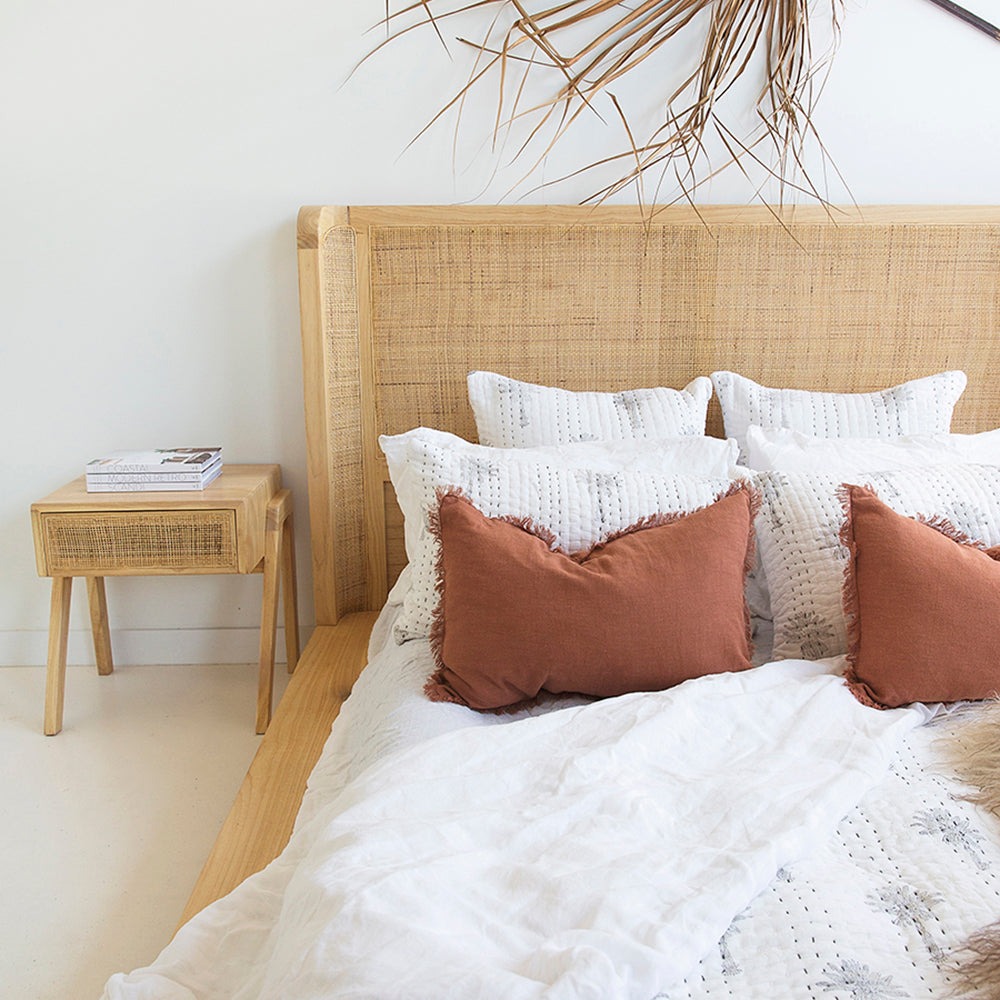 Close-up of the Castaway King Bed headboard with woven rattan detail and natural timber bedside table