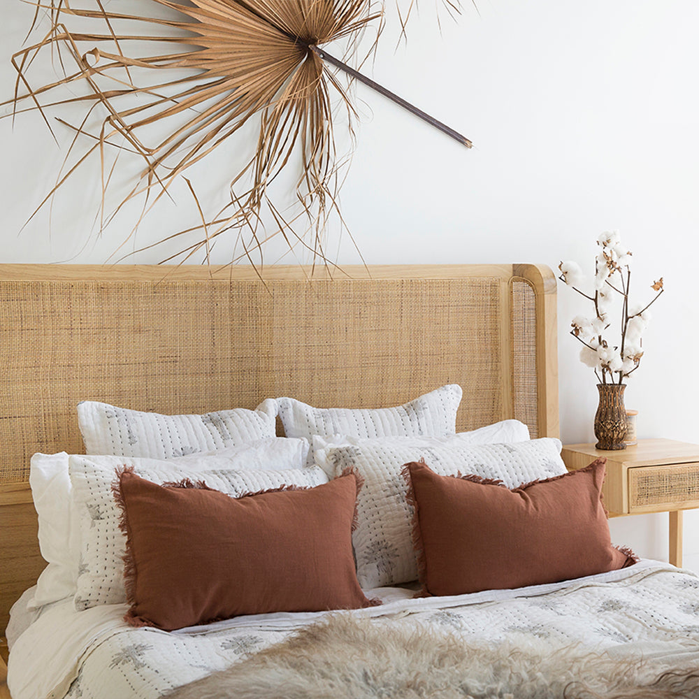 Castaway Queen Bed rattan headboard styled with white bedding, rust cushions and soft neutral throws