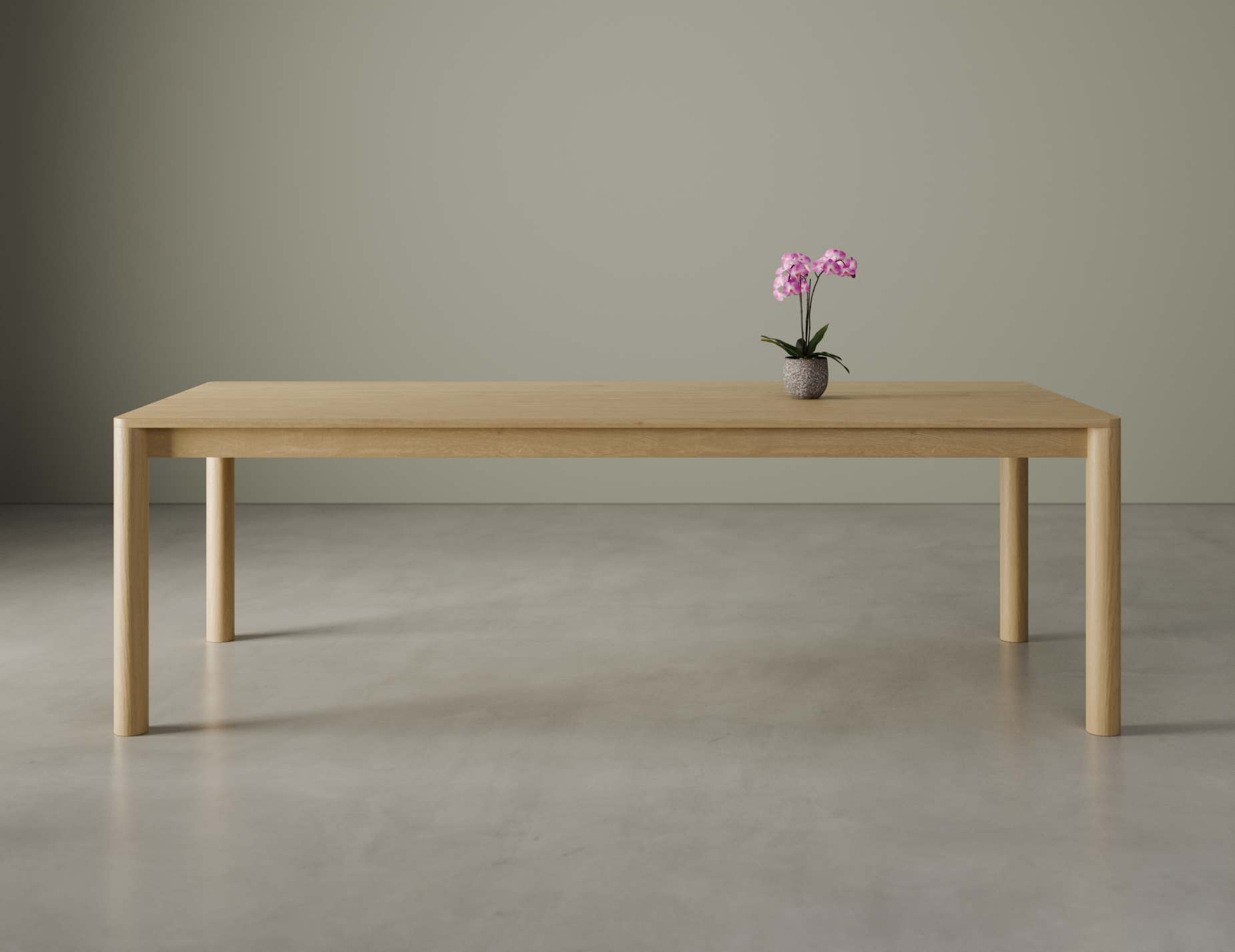 Front view of a large Nordica wooden dining table in natural oak finish with a flower in a vase on a polished concrete floor.