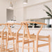 Wishbone Counter Stool in Natural Oak angled view of multiple stools at a kitchen island in a bright open plan home.