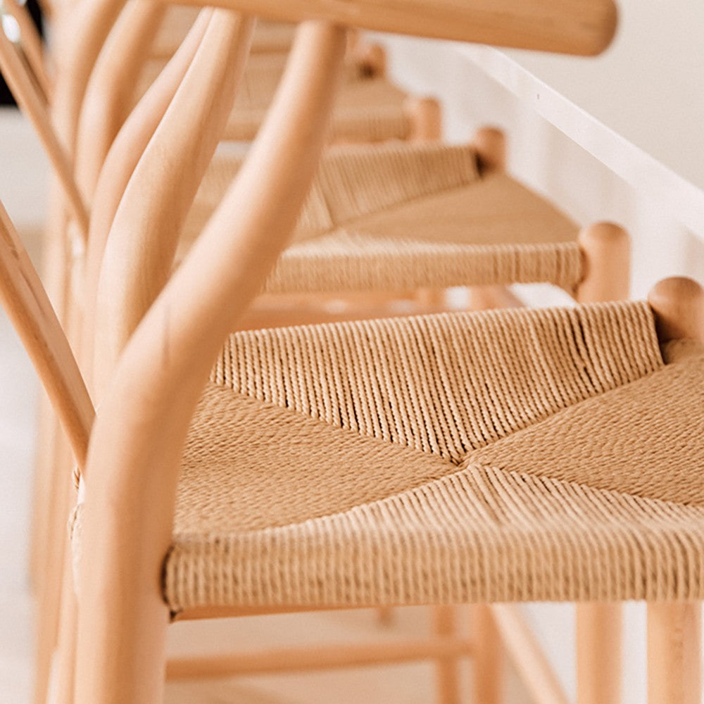 Wishbone Counter Stool in Natural Oak close up of the woven cord seat and curved timber frame beside a white kitchen bench.