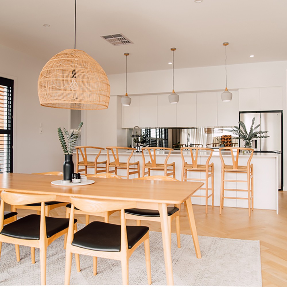 Wishbone Counter Stool in Natural Oak styled at a kitchen bench behind a timber dining table in a warm modern home.