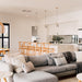 Wishbone Counter Stool in Natural Oak styled at a white island bench behind a grey sofa in an open plan living space.