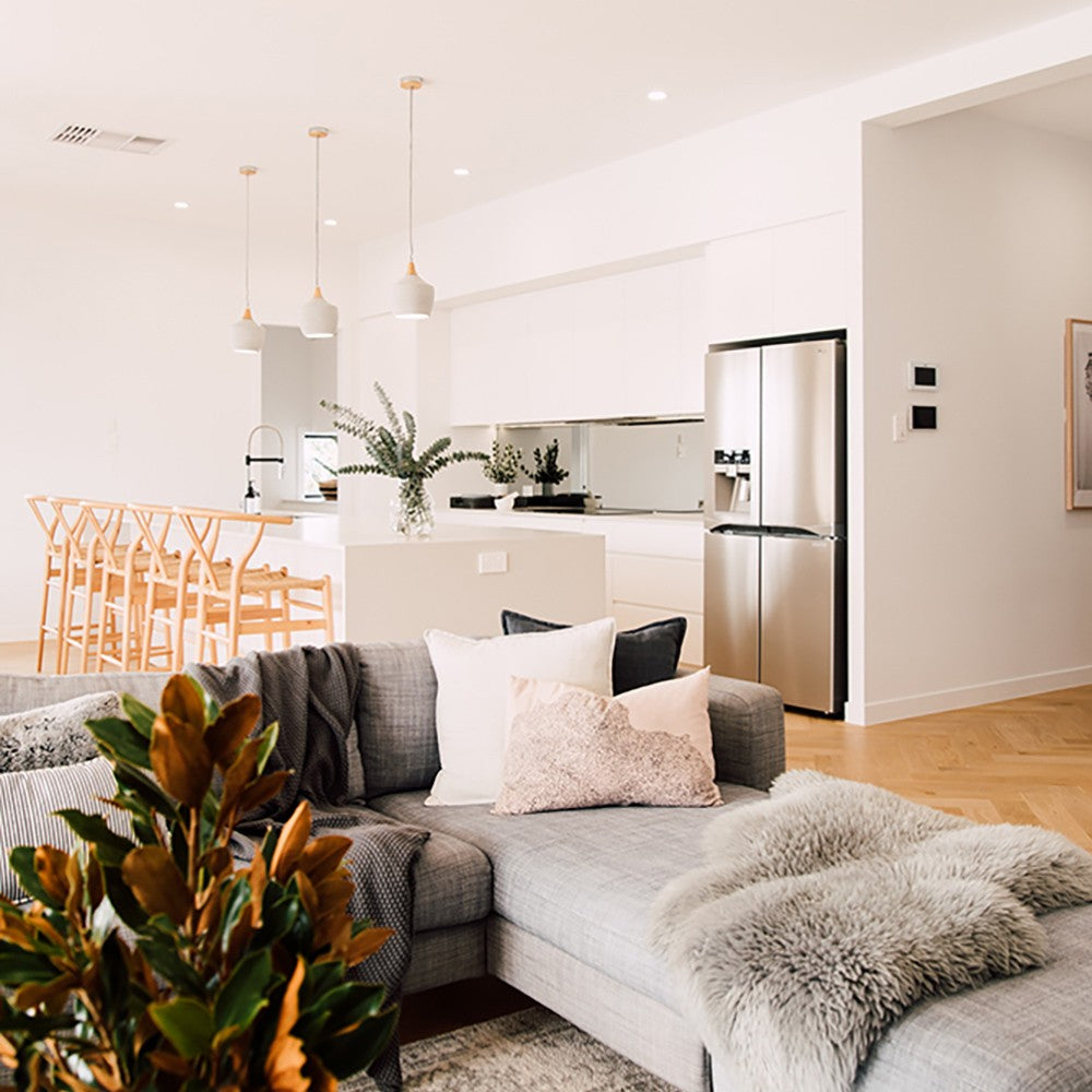 Wishbone Counter Stool in Natural Oak styled at a white kitchen island in an open plan living room with grey sofa and warm timber flooring.