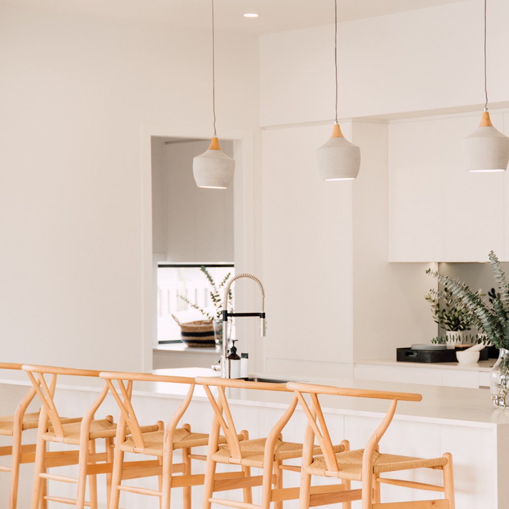 Wishbone Counter Stool in Natural Oak row of stools positioned under pendant lights at a white kitchen island.