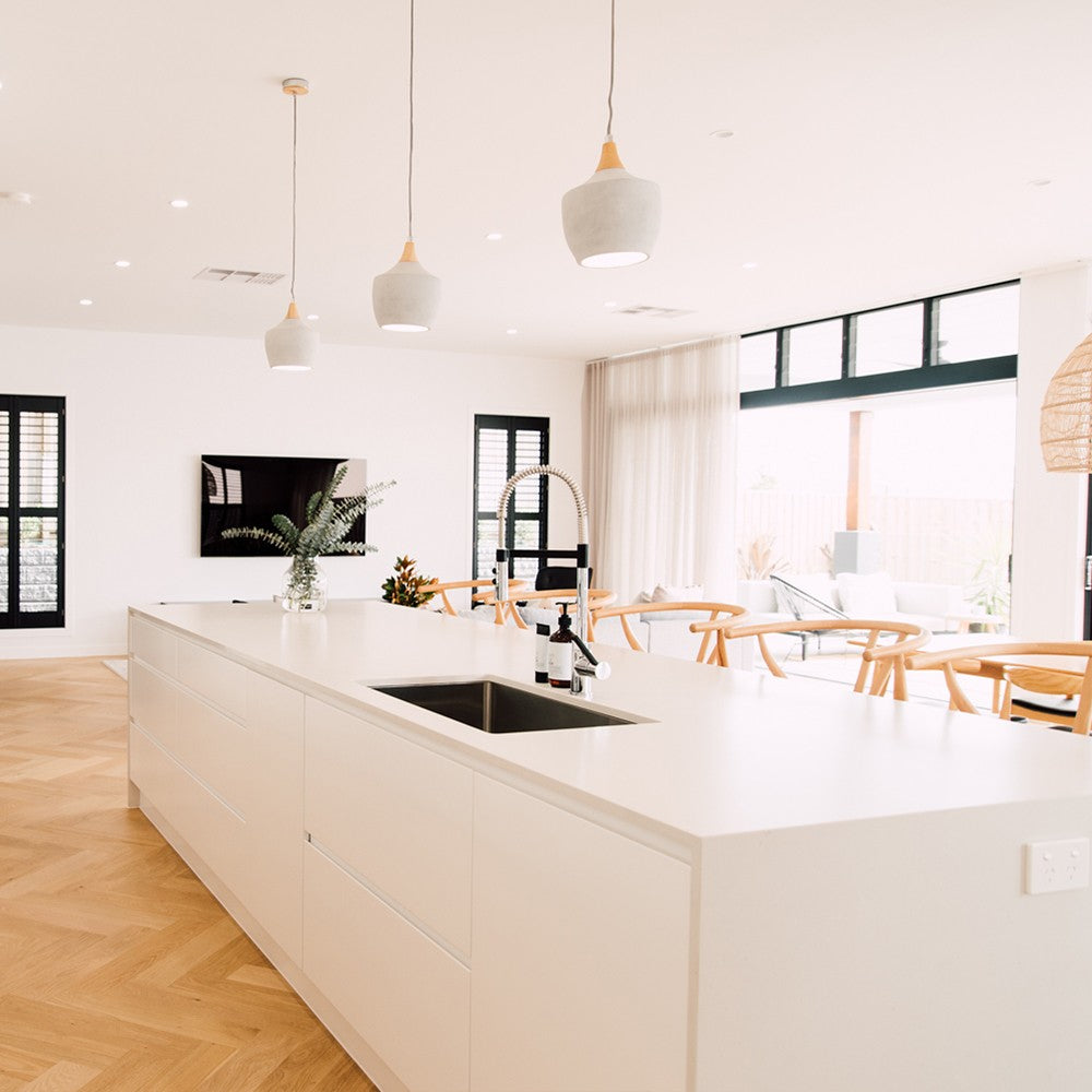 Wishbone Counter Stool in Natural Oak behind a large white kitchen island in a modern open plan coastal kitchen.